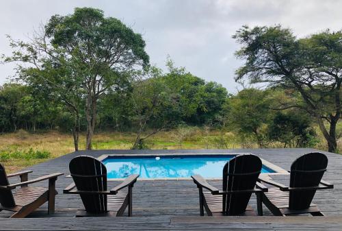a swimming pool with three chairs and a swimming pool at Khangela Private Game Lodge - Self Catering - Bedrooms are 3 Separate Chalets - Hluhluwe in Hluhluwe