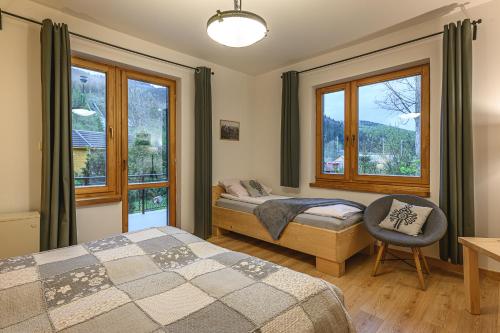 sypialnia z 2 łóżkami, krzesłem i oknami w obiekcie Apartament pod Skocznią w Zakopanem