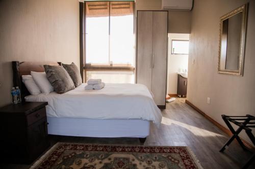 a bedroom with a large bed with a window at Kuwisa Lodge in Bela-Bela