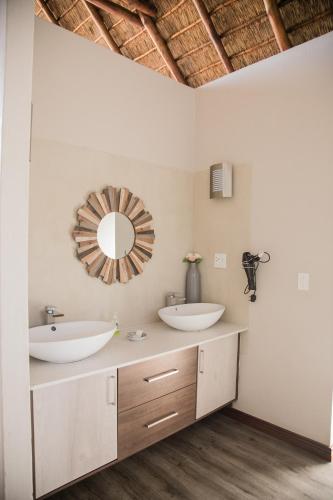 a bathroom with two sinks and a mirror on the wall at Kuwisa Lodge in Bela-Bela