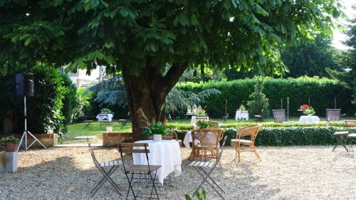 a group of chairs and tables under a tree at VILLA LE ROSE in Cavour
