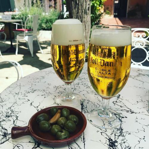 two glasses of beer and a bowl of olives on a table at Hostal Plaja i Pati de Can Plaja in Palafrugell