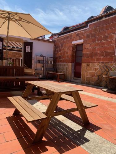 a wooden picnic table with an umbrella on a patio at Yamaharuka Historic House in Jinhu
