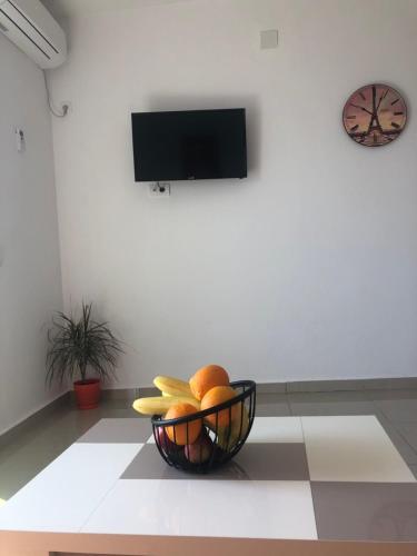 a bowl of fruit on a floor with a clock on a wall at Apartmani Dini in Ulcinj