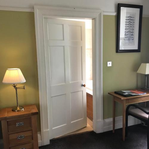 a door in a room with a desk and a lamp at Ashtree House Hotel, Glasgow Airport & Paisley in Paisley