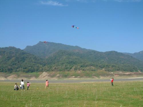 a group of people standing in a field flying a kite at Atunas Holiday Country in Dapu