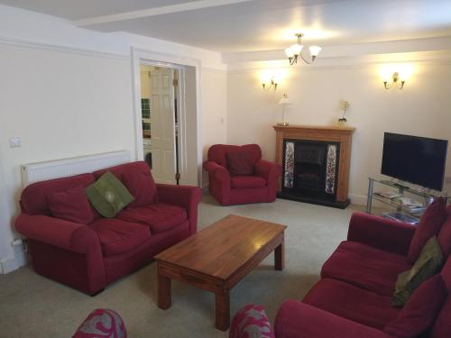 a living room with red furniture and a fireplace at Castle Square Apartments Beaumaris in Beaumaris