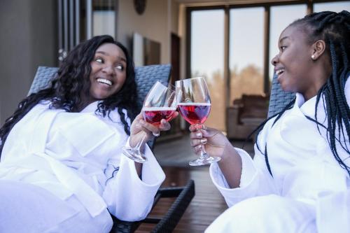 two women holding up glasses of red wine at Kuwisa Lodge in Bela-Bela