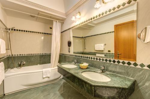 uma casa de banho com 2 lavatórios, uma banheira e um espelho. em Hotel Contilia em Roma