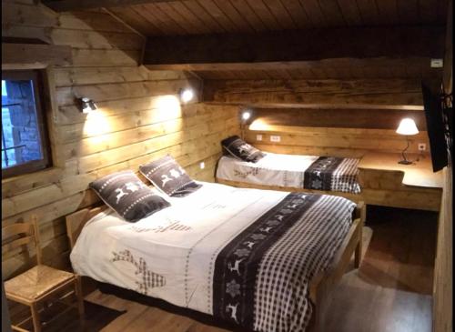 two beds in a room with wooden walls at Chez Maguy Chambres d'hôtes et appartements in Les Angles