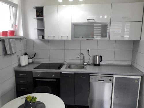 een keuken met witte kasten, een wastafel en een tafel bij HOLIDAY HOME APARTMAN in Visoko