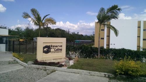 a sign in front of a building with palm trees at Apartamento Eje Cafetero - hermosa vista a piscinas in La Tebaida