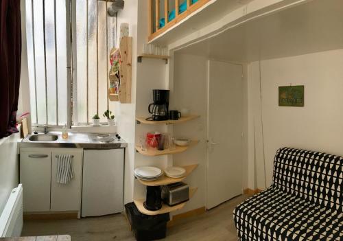 una cocina con fregadero y un sofá en una habitación en Maisonnette studio sur cour, en París
