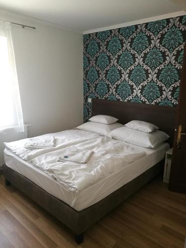 a bedroom with a large white bed with a headboard at Halász Vendégház in Szilvásvárad