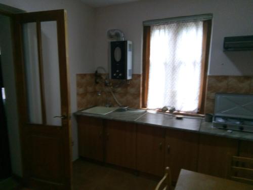 een keuken met een raam en een aanrecht met een televisie bij Guest House Borjomi in Borjomi