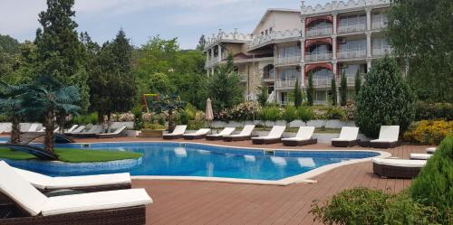 een hotel met een zwembad met ligstoelen en een gebouw bij Hotel Elit Palace and SPA in Balchik
