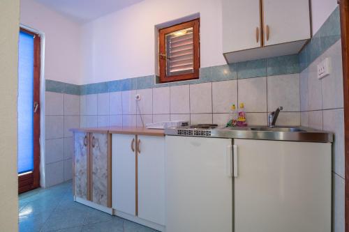 una cocina con armarios blancos y fregadero en Apartmani Dodig en Neum