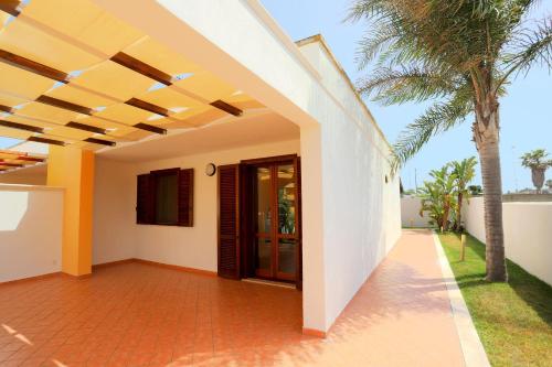 a view of a house with a porch and palm trees at Villetta Mirtillo by TerraSalento in Torre dell'Orso