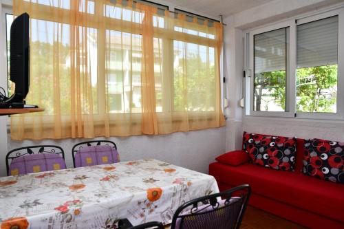 sala de estar con mesa y sofá rojo en Apartments Josip en Rab