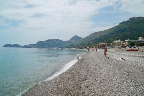 a group of people walking on a beach near the water at Palazzo Durante in Letojanni