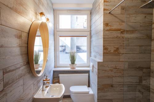 a bathroom with a sink and a toilet and a window at Apartamenty Pocztowa in Bydgoszcz