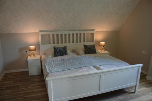 a bedroom with a large white bed with two lamps at Ferienhaus Eifel-Charme in Birgel