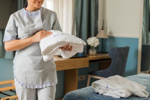 una mujer sosteniendo un montón de toallas en una habitación en La Villa Boutique Hotel, en Budva