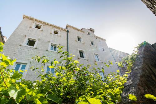 an old stone building with blue windows and trees at La Villa Boutique Hotel in Budva