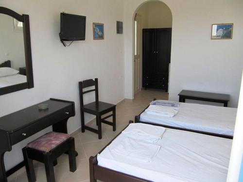 a room with two beds and a chair and a mirror at Argo in Antiparos