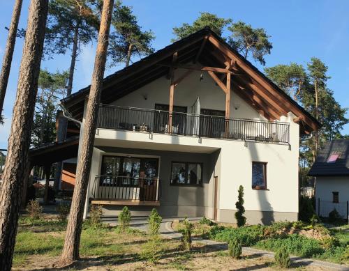 a large white house with a balcony and trees at apartamenty nad jeziorem in Turawa
