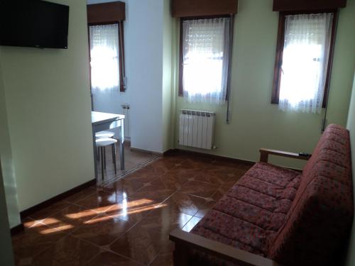 a living room with a couch and a table and windows at Apartamentos Rurales Pernús in Colunga