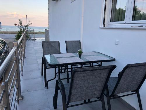 a table and chairs on a balcony with the ocean at Skoulidis Family Apartments in Nea Vrasna