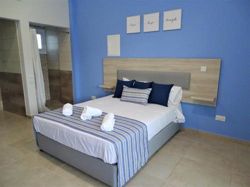 a blue bedroom with a bed with two towels on it at Proteas Mare Suites in Protaras