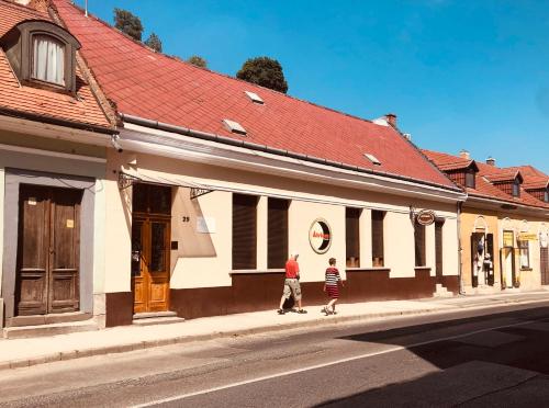 two people walking down a street in front of buildings at Atrium Panzio in Esztergom