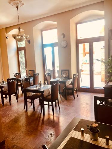 a dining room with tables and chairs and windows at Atrium Panzio in Esztergom