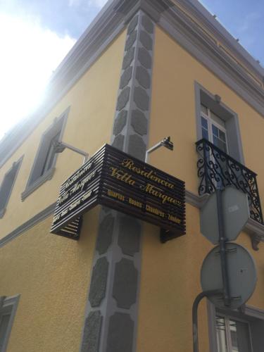 a pole with signs on the side of a building at Villa Marquez in Vila Real de Santo António
