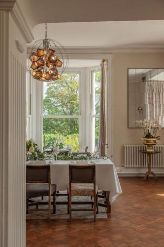 a dining room with a table with chairs and a chandelier at Mansion House Llansteffan in Carmarthen