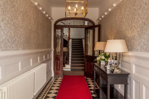 a hallway with a red carpet and a mirror at Mansion House Llansteffan in Carmarthen