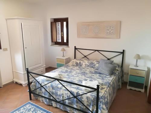 a bedroom with a bed with a blue and white comforter at DAMMUSI IL CARRUBO in Pantelleria