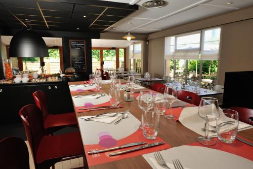 a dining room with a long table with wine glasses at Campanile Cholet in Cholet