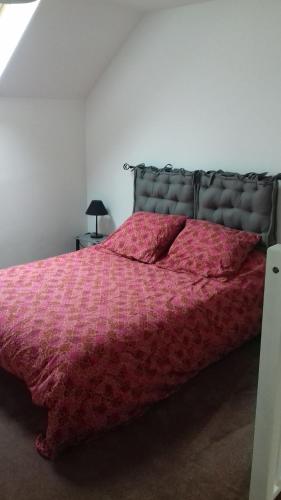 um quarto com uma cama com um edredão rosa em Au Petit Bezion em Sarceaux