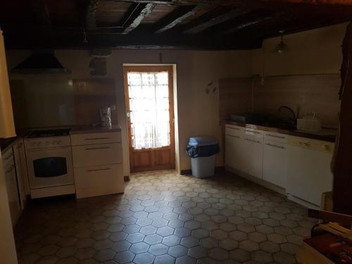 une cuisine avec des placards blancs, une fenêtre et une porte dans l'établissement Maison au village du livre, à Montolieu