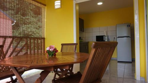 a dining room table with chairs and a refrigerator at Les Gites du Bonheur in Deshaies