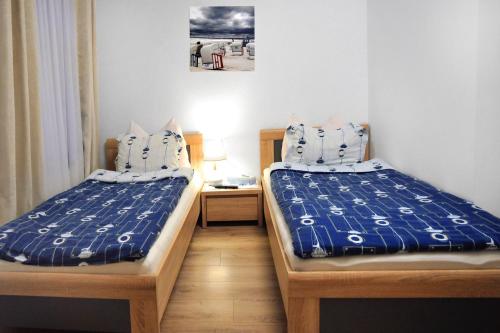 a room with two beds with blue and white sheets at Muszelka - Pokoje Gościnne in Świnoujście
