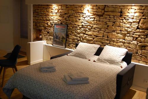 Bett in einem Zimmer mit einer Steinmauer in der Unterkunft PETIT GITE EN BRACONNE in La Rochette