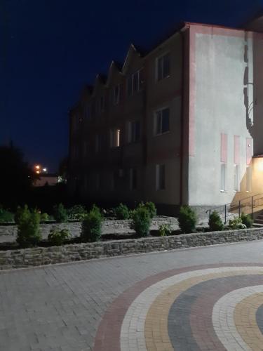 un edificio por la noche con una calle adoquinada en Готель Адріана, en Dunaivtsi