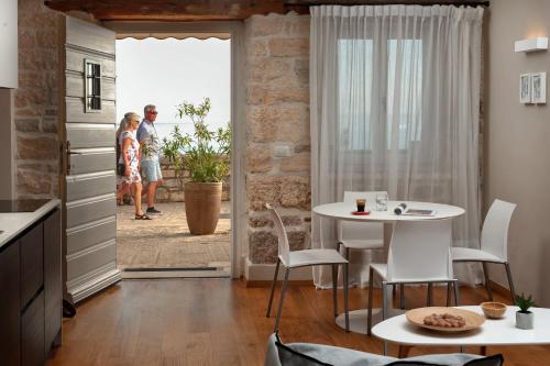 a kitchen with a table and two people standing outside a door at Angelo d'Oro Apartment Monte in Rovinj