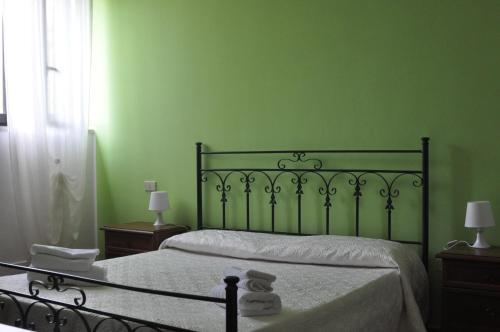 a bedroom with green walls and a bed with white sheets at Villa Lidia in Paola