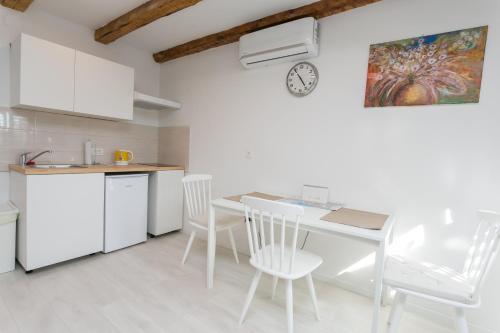 a kitchen with a table and chairs and a clock at Apartment Relax in Rijeka