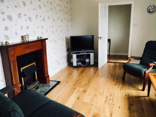 a living room with a fireplace and a flat screen tv at Brook Cottage in Portree